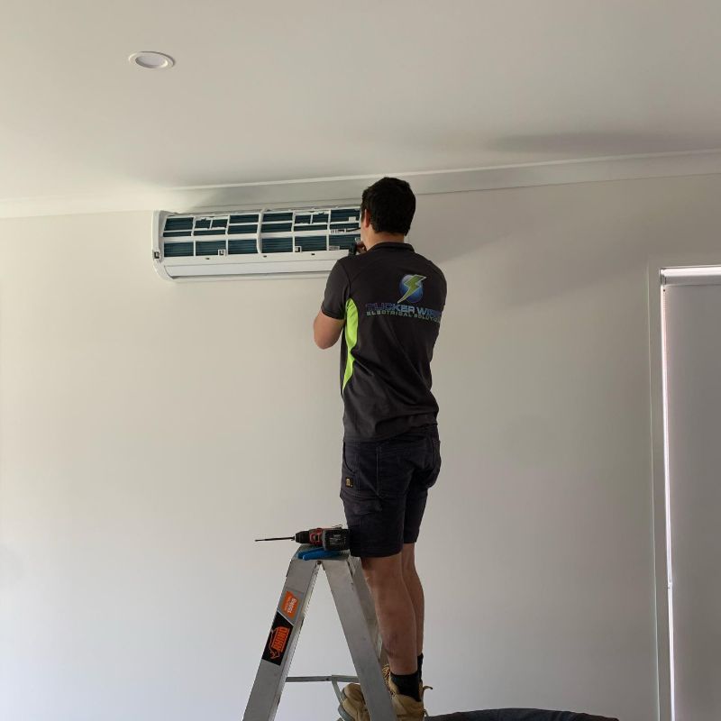 Technician on a stepladder working on a wall-mounted split system