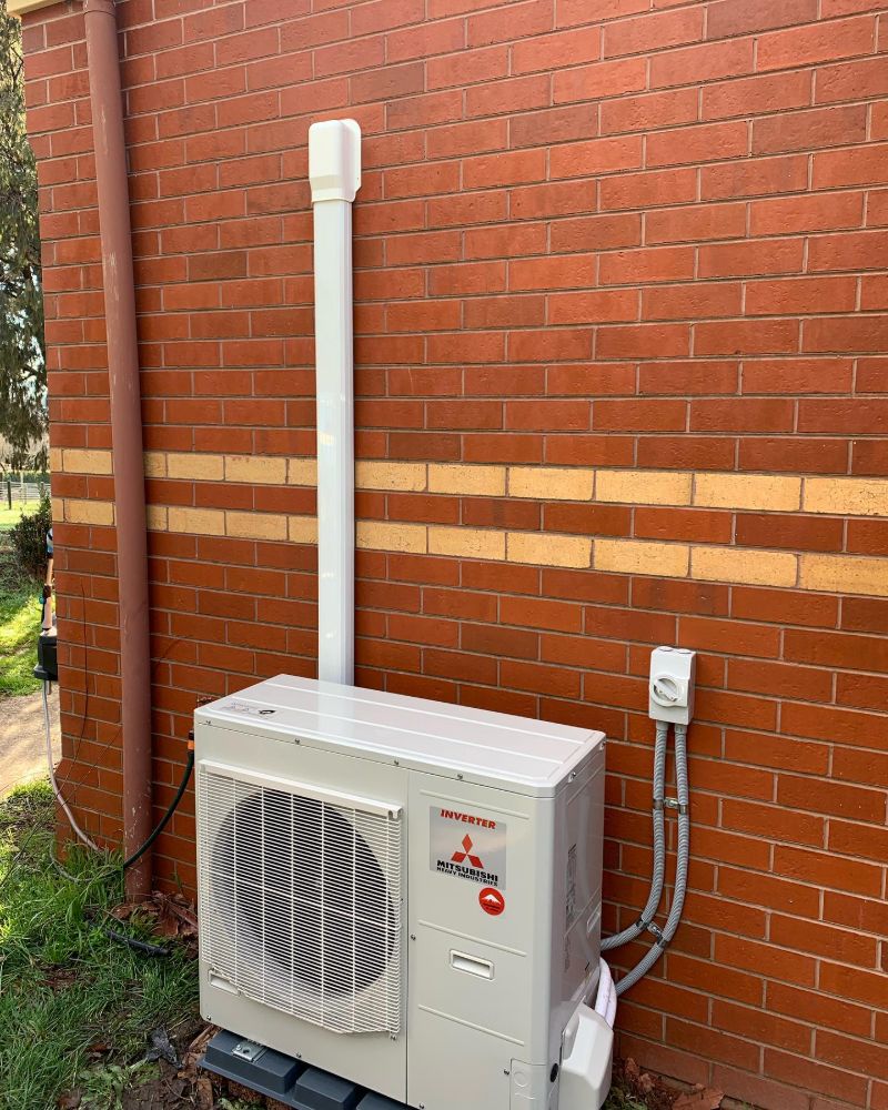Outdoor air conditioning unit on a slab beside a red brick wall