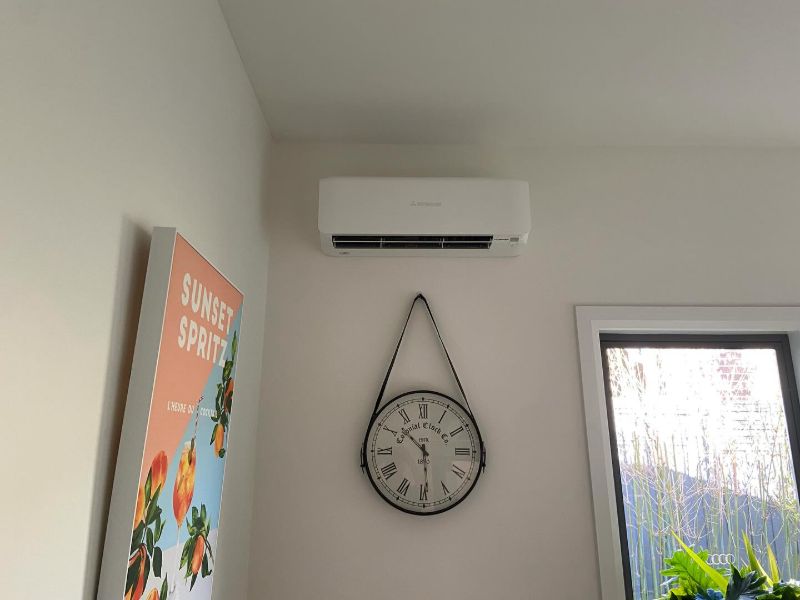 Split system air conditioner above a wall clock in a bright room
