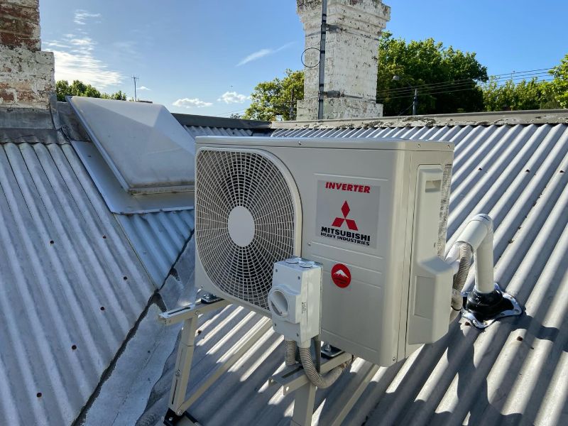 Mitsubishi Heavy Industries inverter outdoor unit on a roof frame near a chimney