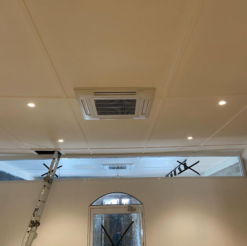 Ceiling cassette air conditioner in a room with downlights