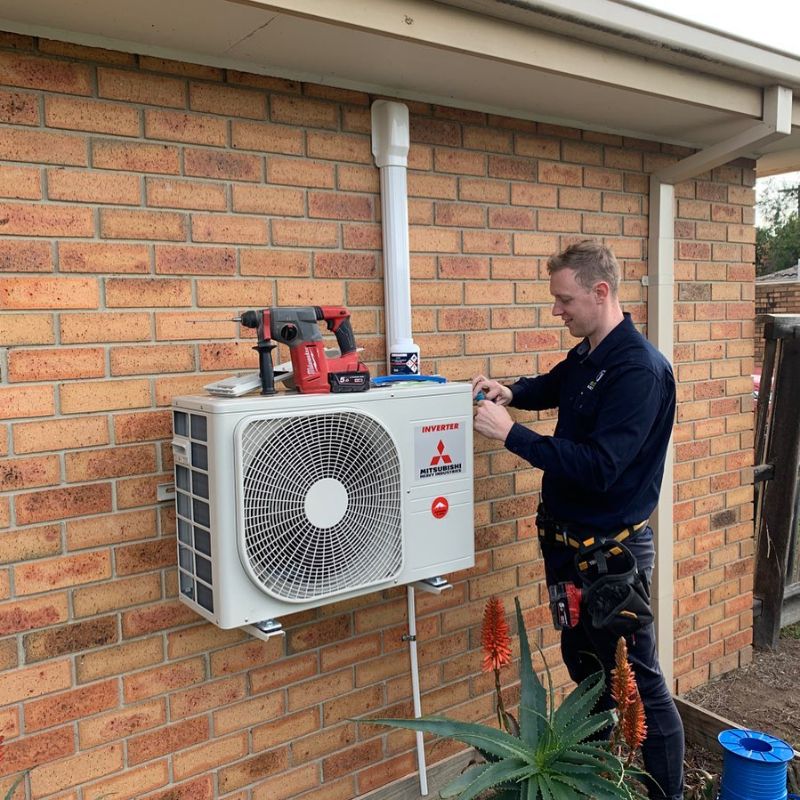 Technician working on an outdoor unit mounted on a brick wall