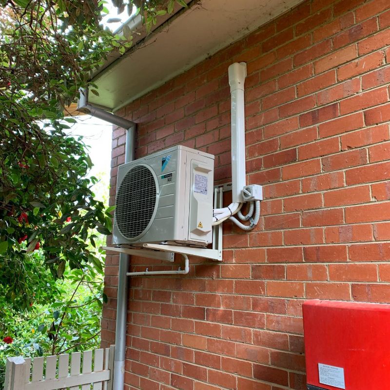 Outdoor air conditioning unit on a wall bracket on a red brick house