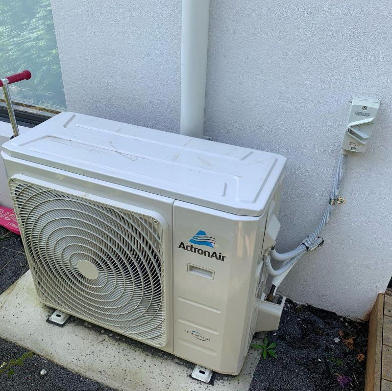 ActronAir outdoor unit on a concrete pad beside a rendered wall