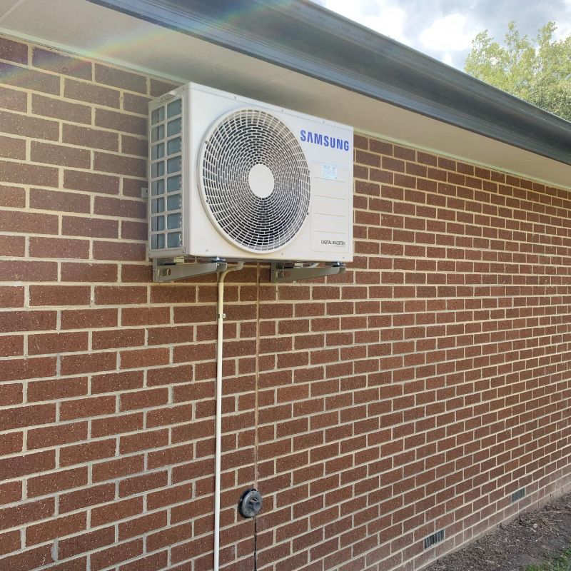 Samsung outdoor unit mounted high on a brick wall under the eaves