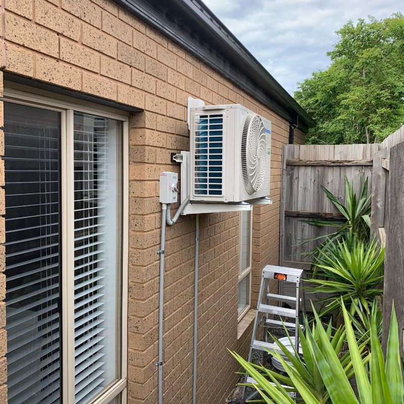 Outdoor unit on a wall bracket beside a window in a side passage