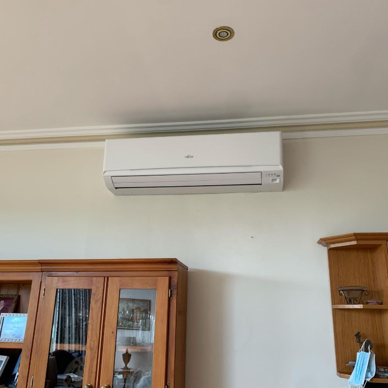 Split system air conditioner on a wall above a timber display cabinet