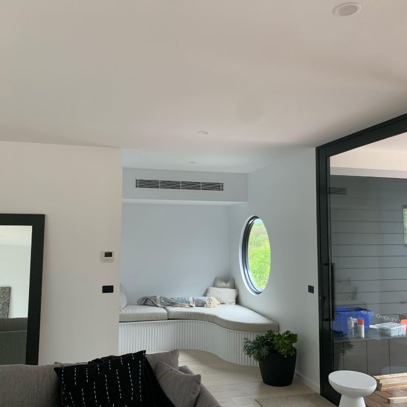Ducted air conditioning vent above a window seat with a round window