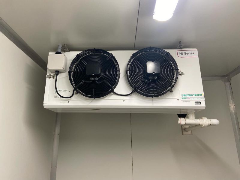 Two-fan cool room evaporator mounted on a white panel wall